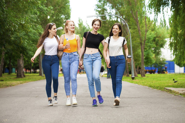 Happy women in blue jeans walking in summer park - Valokuva, kuva