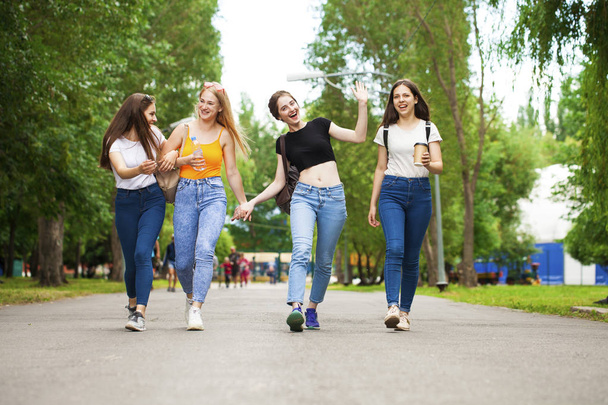 Happy women in blue jeans walking in summer park - Photo, Image