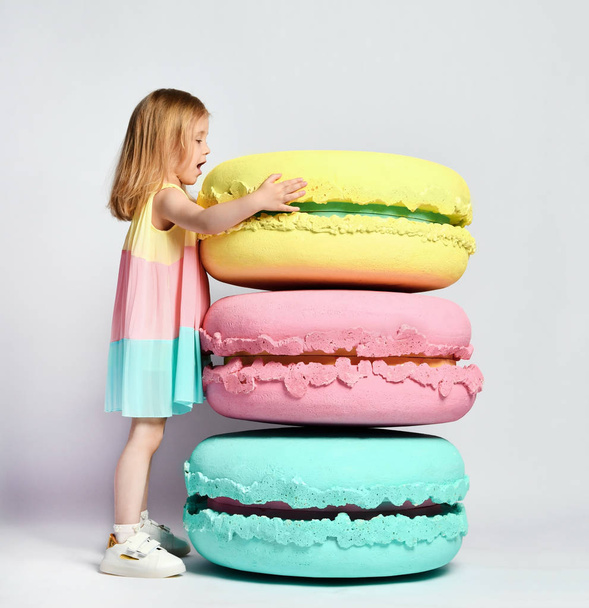 Cute little girl in bright clothes have fun at the birthday party fun room decoration candy macarons - Photo, Image