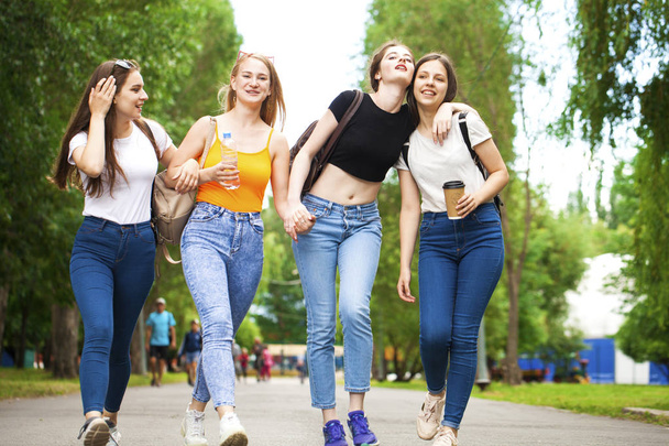 Happy women in blue jeans walking in summer park - Zdjęcie, obraz