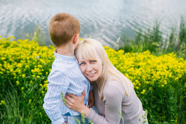 幸せな家族:湖の近くの草の上に座っている息子と母親 - 写真・画像