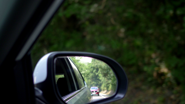 auto Chase concept. uitzicht vanaf het raam van de auto. in de achteruitkijkspiegel is zichtbare rode auto-. - Video