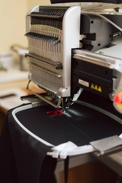 Вышивка текста на швейной машинке промышленного масштаба. машина вышивает букву f на ткани
. - Фото, изображение