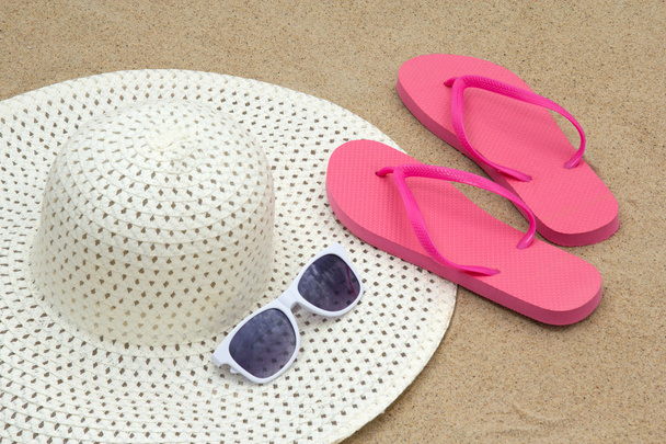 red flip flops, sunglasses and hat on sandy beach - Photo, Image