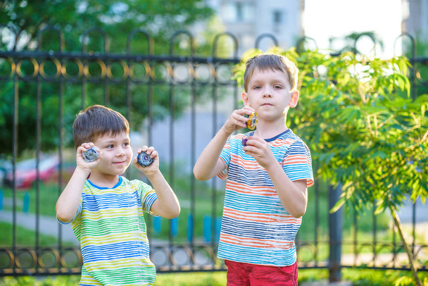 два хлопчика грають з обертовим верхом на відкритому повітрі
 - Фото, зображення