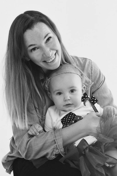 baby in the arms of the mother. on white background Woman holding a child. Fashion for girl. - Foto, Imagen