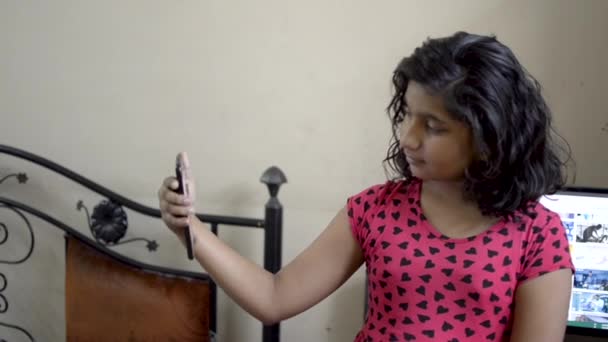 Cute adorable Indian Asian caucasian happy girl child taking selfie making pout on mobile phone and checking front view portrait  - Footage, Video