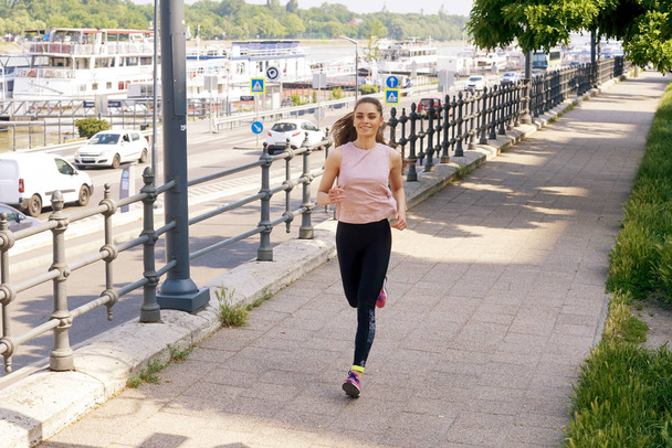 Full length shot of young woman running in the city. - Valokuva, kuva