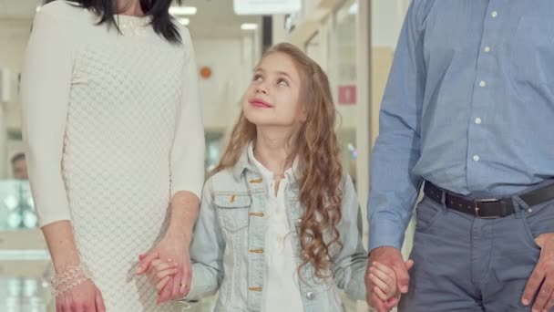 Aranyos kislány mosolyogva, hogy a kamerát, kezében kezét a szüleivel - Felvétel, videó