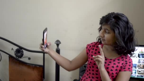 Χαριτωμένο κομψό Ινδικό Ασίας Καυκάσιος ευτυχισμένος κορίτσι παιδί λαμβάνοντας selfie κάνοντας μούτρα στο κινητό τηλέφωνο πρόσοψη πορτρέτο  - Πλάνα, βίντεο