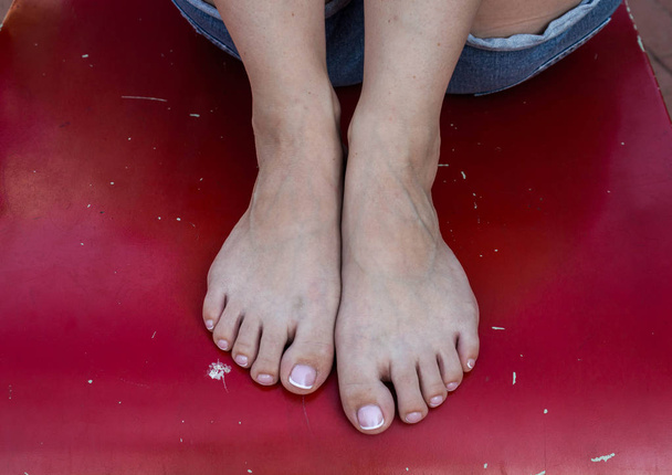güzel bir pedikür ve kırmızı bir arka plan üzerinde kadın ayakları - Fotoğraf, Görsel