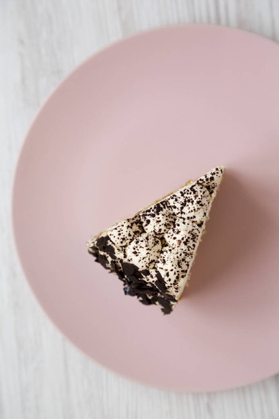 ein Stück Tiramisu-Kuchen auf einem rosa Teller auf einem weißen Holzrücken - Foto, Bild