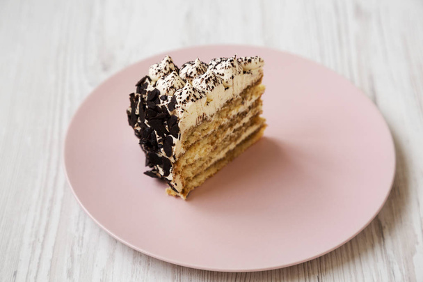 Kawałek tiramisu ciasto na różowym talerzu na białym drewnianym stole - Zdjęcie, obraz