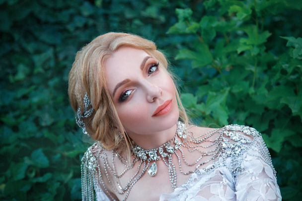 portrait photo of pretty young woman with light white skin and delicate natural make-up, girl with blond braided hair with silver jewelry looks straight into camera, chic image of prom or party - Photo, Image