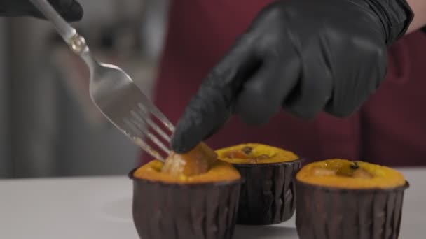 Baker stuffing muffins with bananas. Confectioner making banana cupcakes. Homemade concept. Close up view of hand in black glove. Step by step - Imágenes, Vídeo