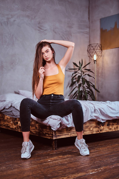 attraktive junge Frau sitzt auf ihrem Bett - Foto, Bild