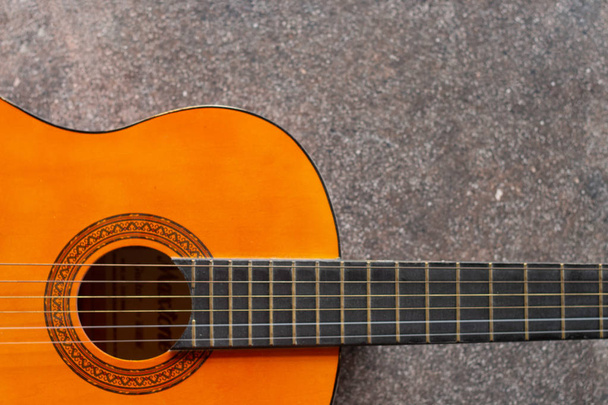 木製の6弦ギター。コンクリートの背景に横たわるギターのクローズアップ - 写真・画像