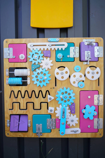 kleurrijke drukke Board gemaakt van hout met veel verschillende dingen op het. ontwikkeling kinderspel voor motorische vaardigheden van het kind. Niemand. - Foto, afbeelding