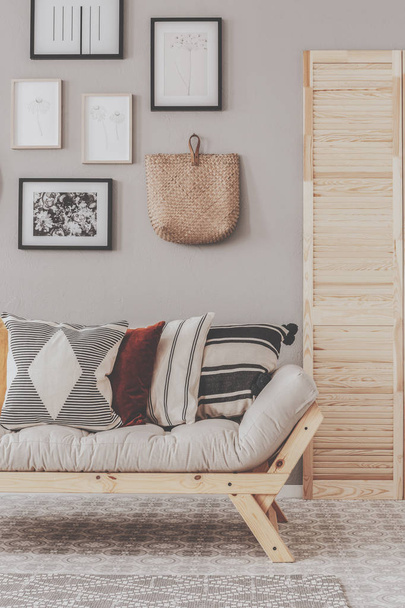 Wicker bag and posters in frames on beige wall of natural living room interior - Φωτογραφία, εικόνα