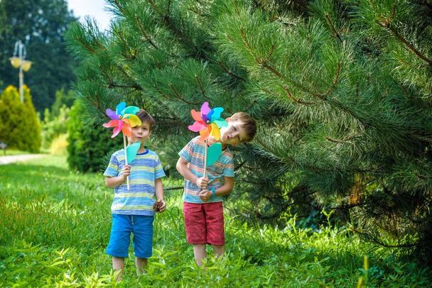 Двое счастливых детей играют в саду с колесиком ветряной мельницы. Адо
 - Фото, изображение