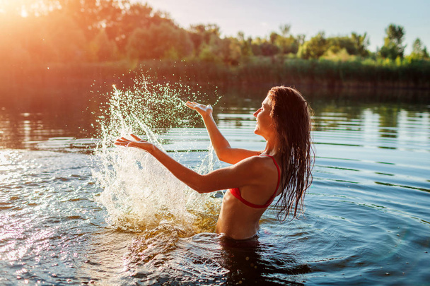 Молодая женщина в бикини играет в воде и делает всплеск. Летний отдых
 - Фото, изображение