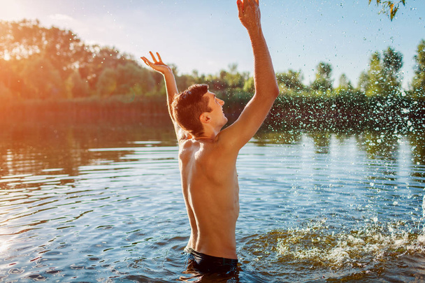 junger Mann im Wasser und macht Spritzer. Sommerferien - Foto, Bild