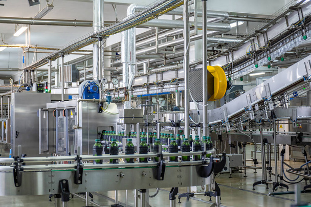 Transportband of lijn in dranken fabriek met moderne geautomatiseerde industriële machine-apparatuur. Plastic PET-flessen met vers organisch SAP in fabrieks interieur - Foto, afbeelding