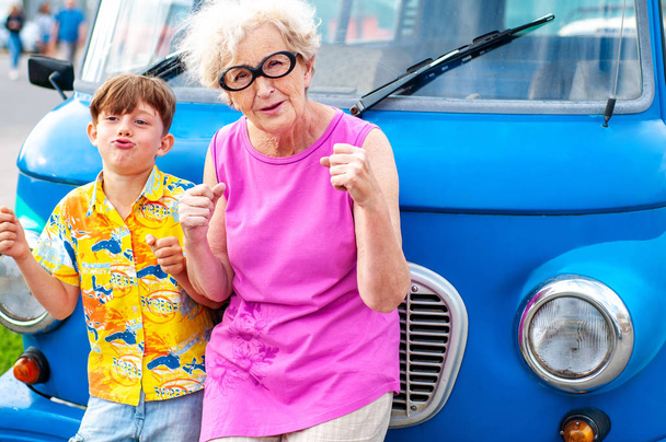 Modne, wesoła babcia z dziadkiem są oszukiwanie wokół retro samochód imitujące jazdy. Letnie rodzinne wakacje i podróże - Zdjęcie, obraz