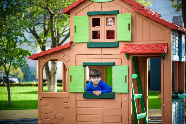 İki küçük çocuk birlikte oynuyorlar ve eğleniyorlar. Çocuk parkında kardeşlerin yaşam tarzı aile anı. Çocuklar ağaç evde oynarlar. İpe ya da merdivenlere tırmanırlar. - Fotoğraf, Görsel