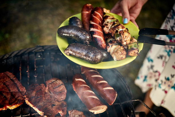 Juicy sausages straight from grill on green plate from hot barbecue  - Photo, Image