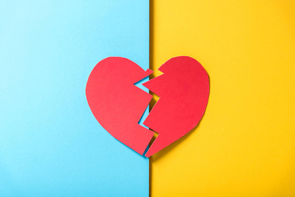 red paper broken heart on yellow and blue background - Foto, immagini