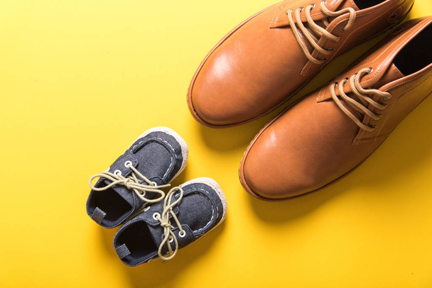zapatos del padre y del hijo sobre fondo amarillo, concepto del día del padre
 - Foto, imagen