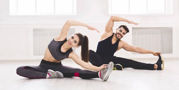 Young fit couple stretching on the floor in studio - Photo, Image