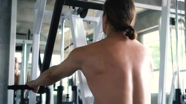 Gömleksiz kaslı adam spor salonunda makinede oturan kablo satır egzersiz yapıyor - Video, Çekim