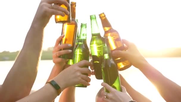 Csapat sörösüvegekkel és tánc zenére egy városi partin a parkban naplementekor, sörösüvegek sziluett - Felvétel, videó