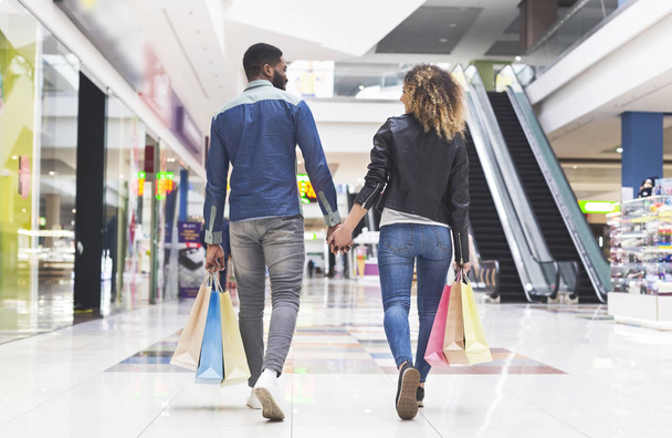 Αφρικάνικο ζευγάρι με σακούλες για ψώνια με τα πόδια από το Mall - Φωτογραφία, εικόνα