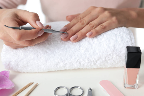 Vrouw bereidt nagelriemen voor aan tafel, close-up. Manicure thuis - Foto, afbeelding