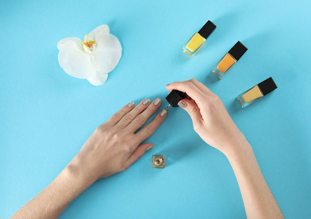 Woman applying nail polish on color background, top view - Foto, Bild