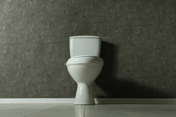 Nouveau bol de toilette près du mur gris à l'intérieur
 - Photo, image