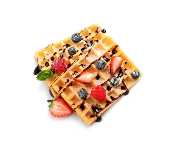 Yummy waffles with berries and chocolate syrup on white background, top view - Foto, imagen