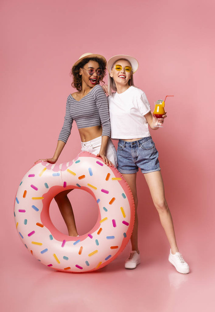 Positieve vriendinnen genieten van vakantie met opblaasbare ring en cocktail - Foto, afbeelding
