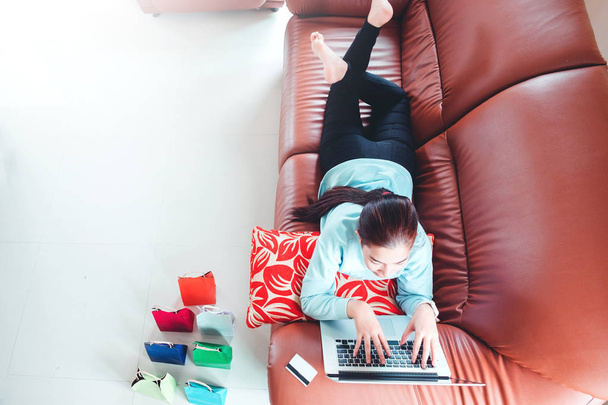 Woman with laptop shopping online with debit card on sofa in hom - Foto, Imagem