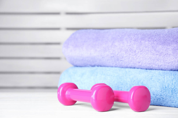 Vinyl dumbbells and towels on table, space for text - Photo, Image
