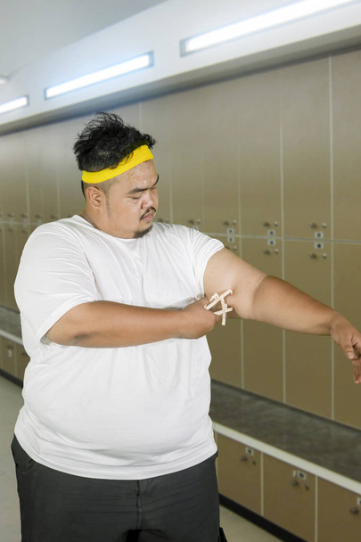 Obese man measures fat layer of his arm - Valokuva, kuva