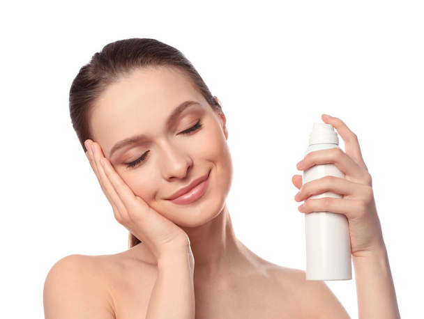 Young woman applying thermal water on face against white background. Cosmetic product - Foto, imagen