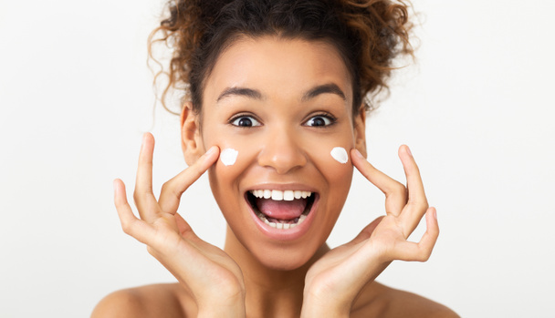 Bőrápolás. Izgatott nő alkalmazása arckrém - Fotó, kép