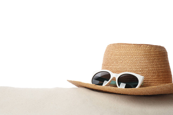 Шляпа и солнцезащитные очки на песке на белом фоне, место для текста. Стильные пляжные принадлежности
 - Фото, изображение