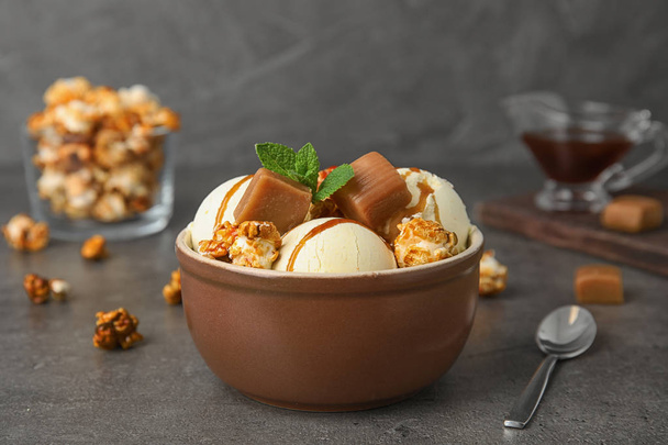 Delicious ice cream with caramel and popcorn in bowl on table - Valokuva, kuva