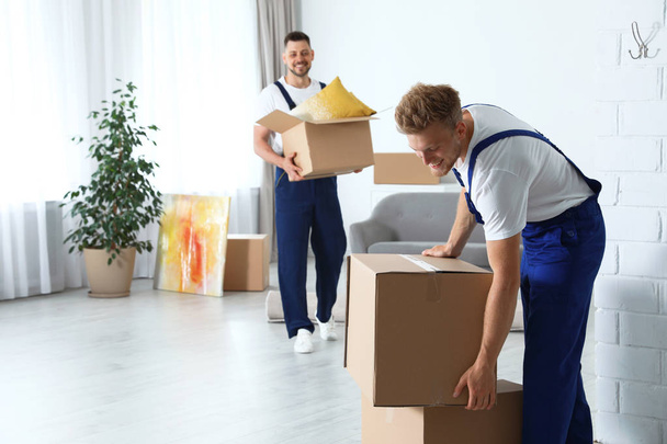 Moving service employees with cardboard boxes in room - Foto, Bild