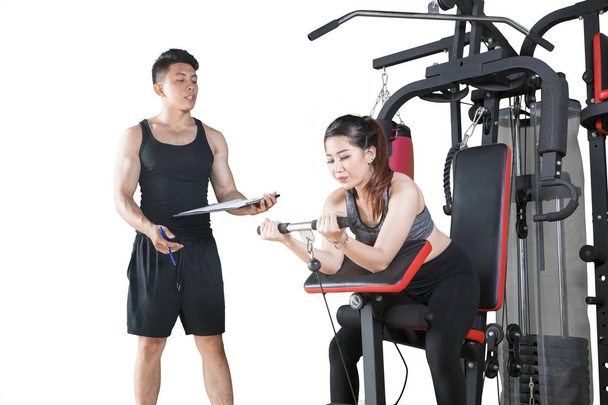 Mulher usa máquina de exercícios com seu treinador
 - Foto, Imagem